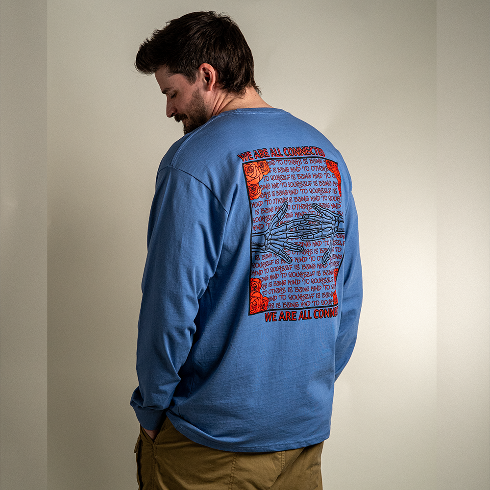 Model wearing blue Kindness Long Sleeve Tee – back graphic showing ‘Being Kind to Others’ repeating message