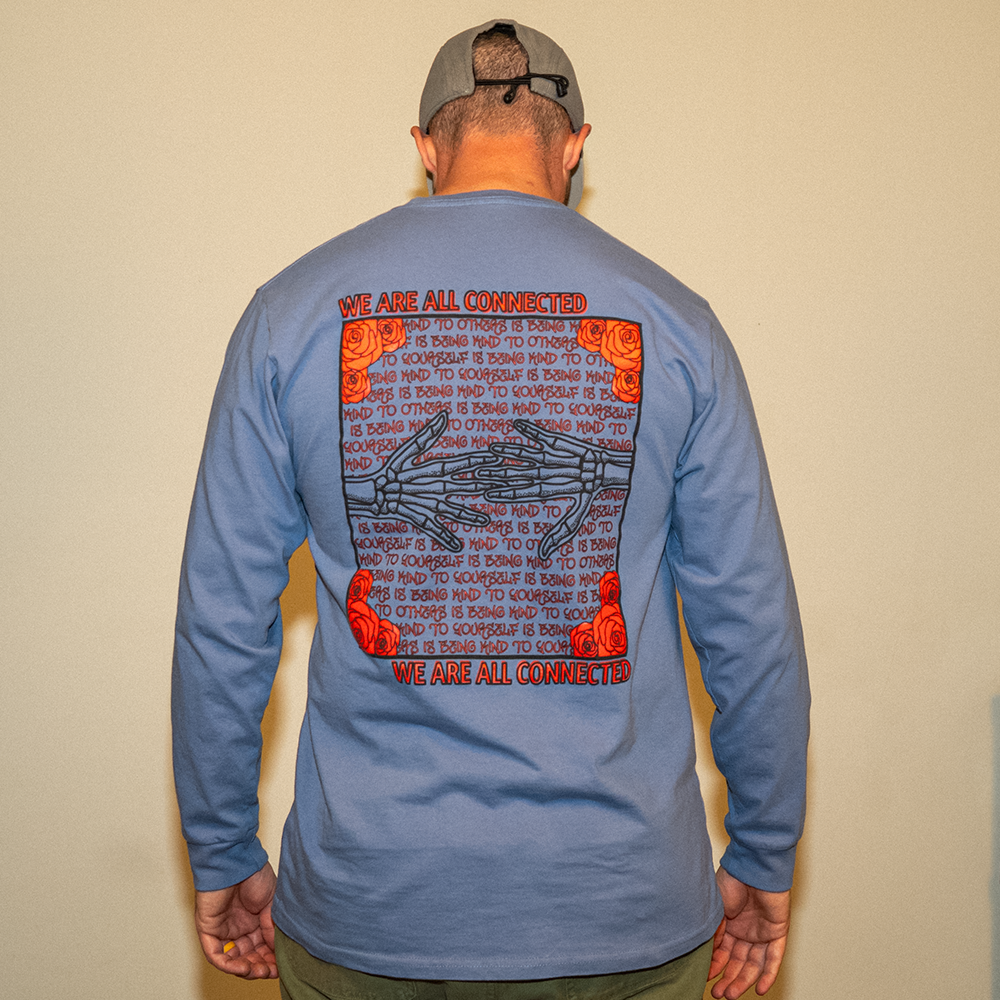 Model wearing blue Kindness Long Sleeve Tee – back graphic showing ‘Being Kind to Others’ repeating message