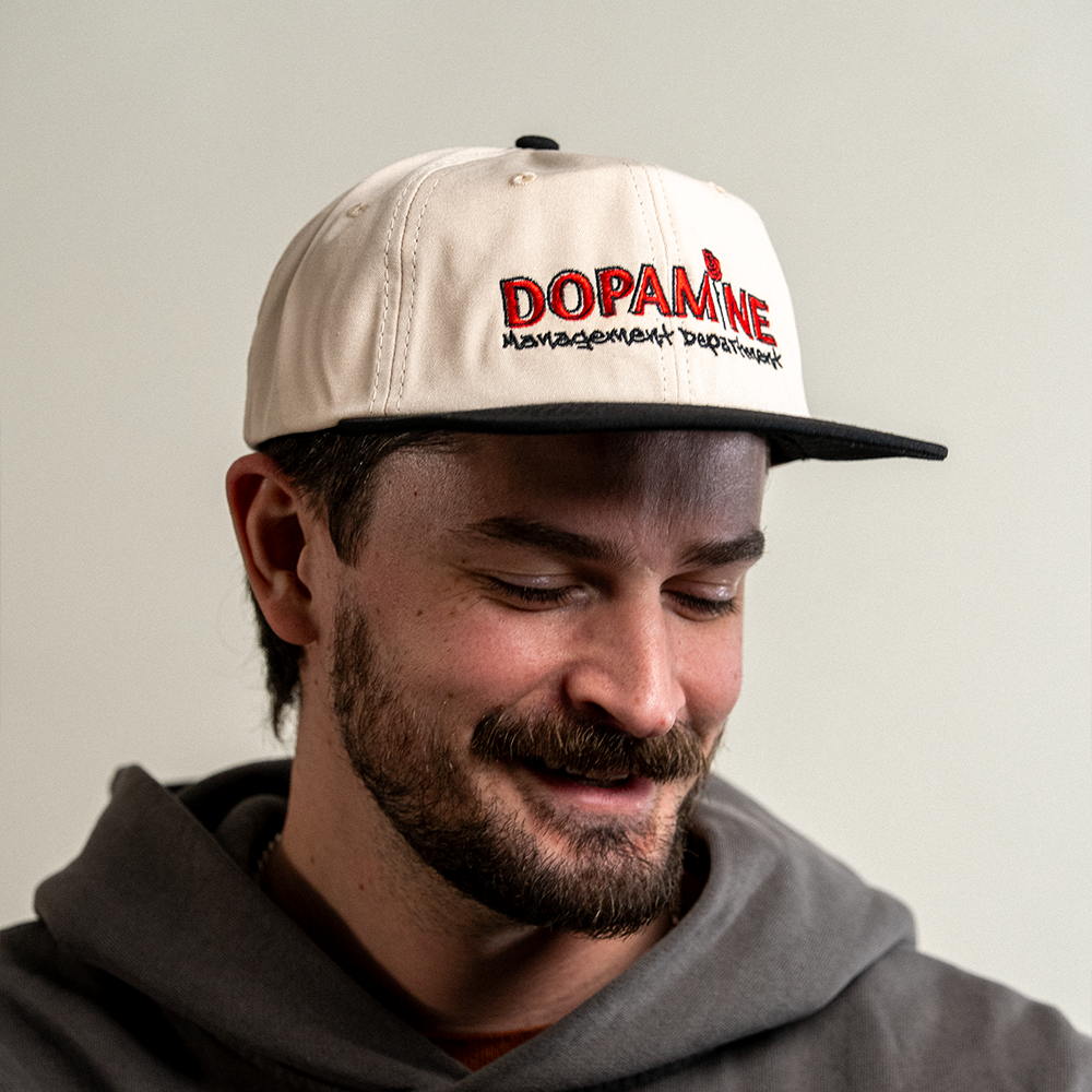 Man smiling looking down while wearing the Rose Logo Hat.