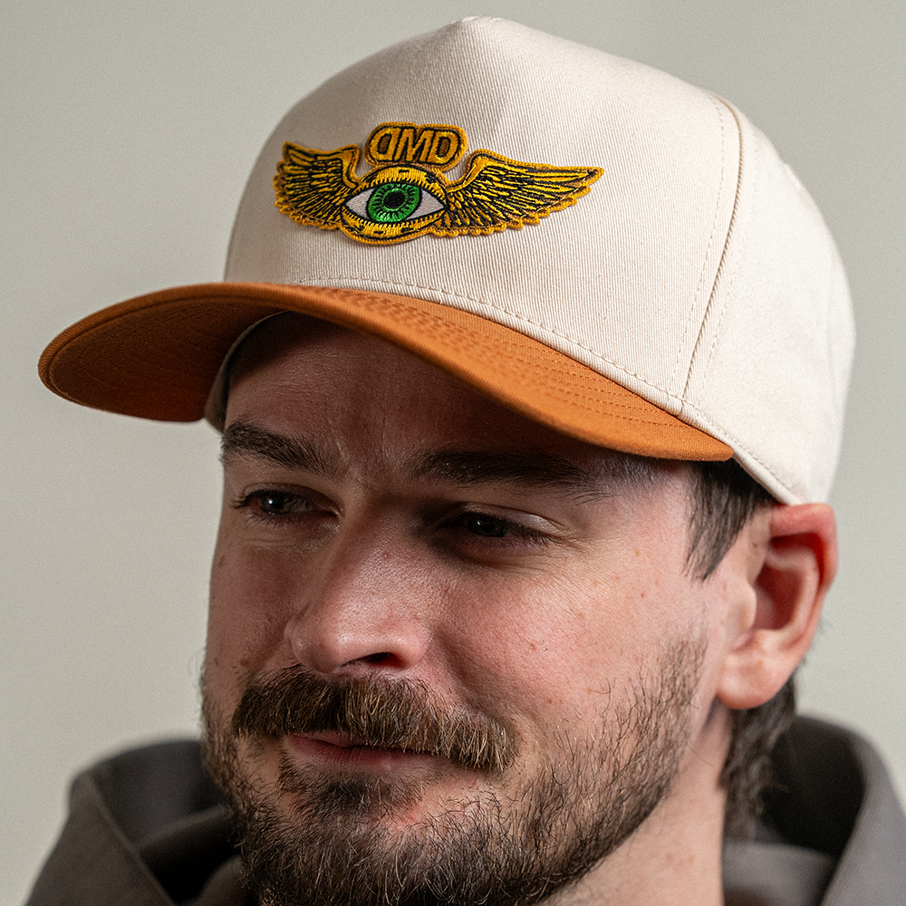 Model wearing the Flying Eye Two-Toned Hat by Dopamine Management Department with beige crown and caramel bill