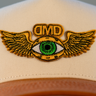 Close-up of Flying Eye embroidery on DMD hat – gold wings and green eye