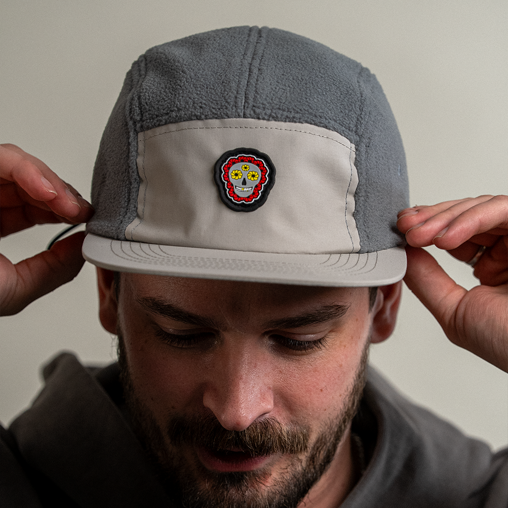 Front view of model looking down wearing Skull Flower Fleece 5 Panel hat showing PVC skull flower patch