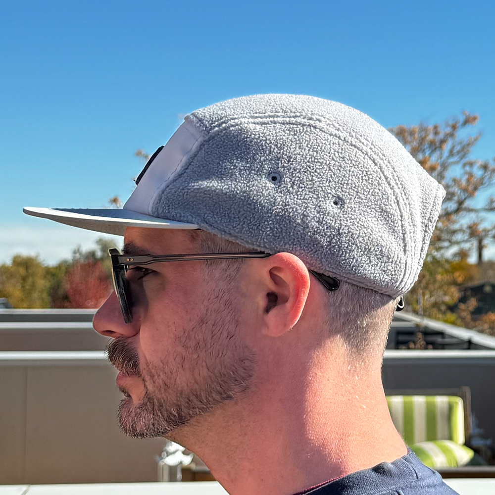 Profile view of model wearing Skull Flower Fleece 5 Panel hat in natural outdoor light