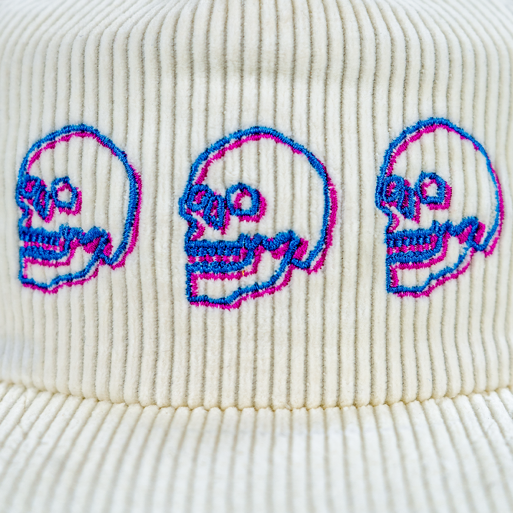 Close-up of embroidered neon blue and pink skull design on corduroy hat