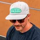 Man wearing Dopamine Management Department Warp Patch Hat and sunglasses, against an orange wall.