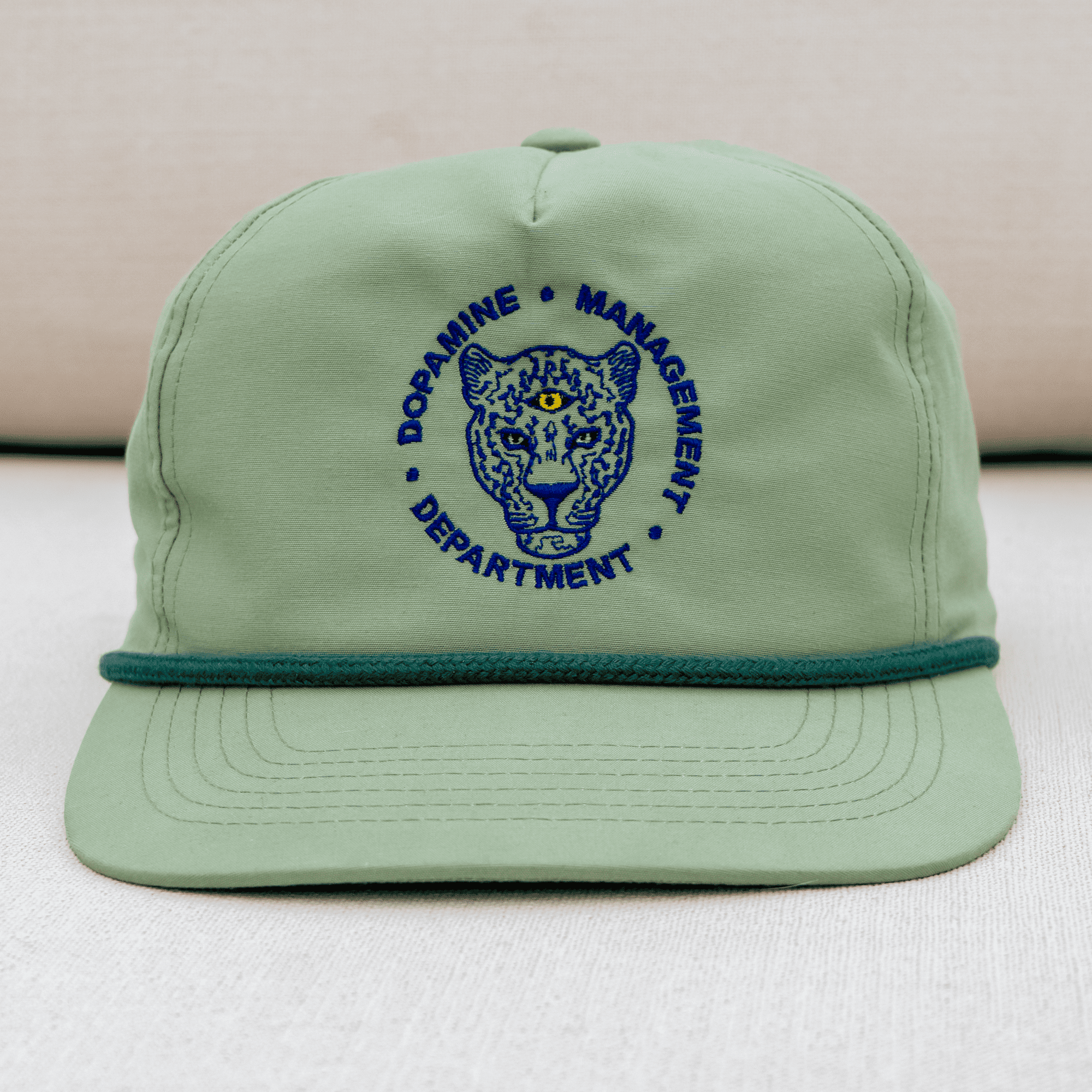 Green cap with blue embroidered design on a light background