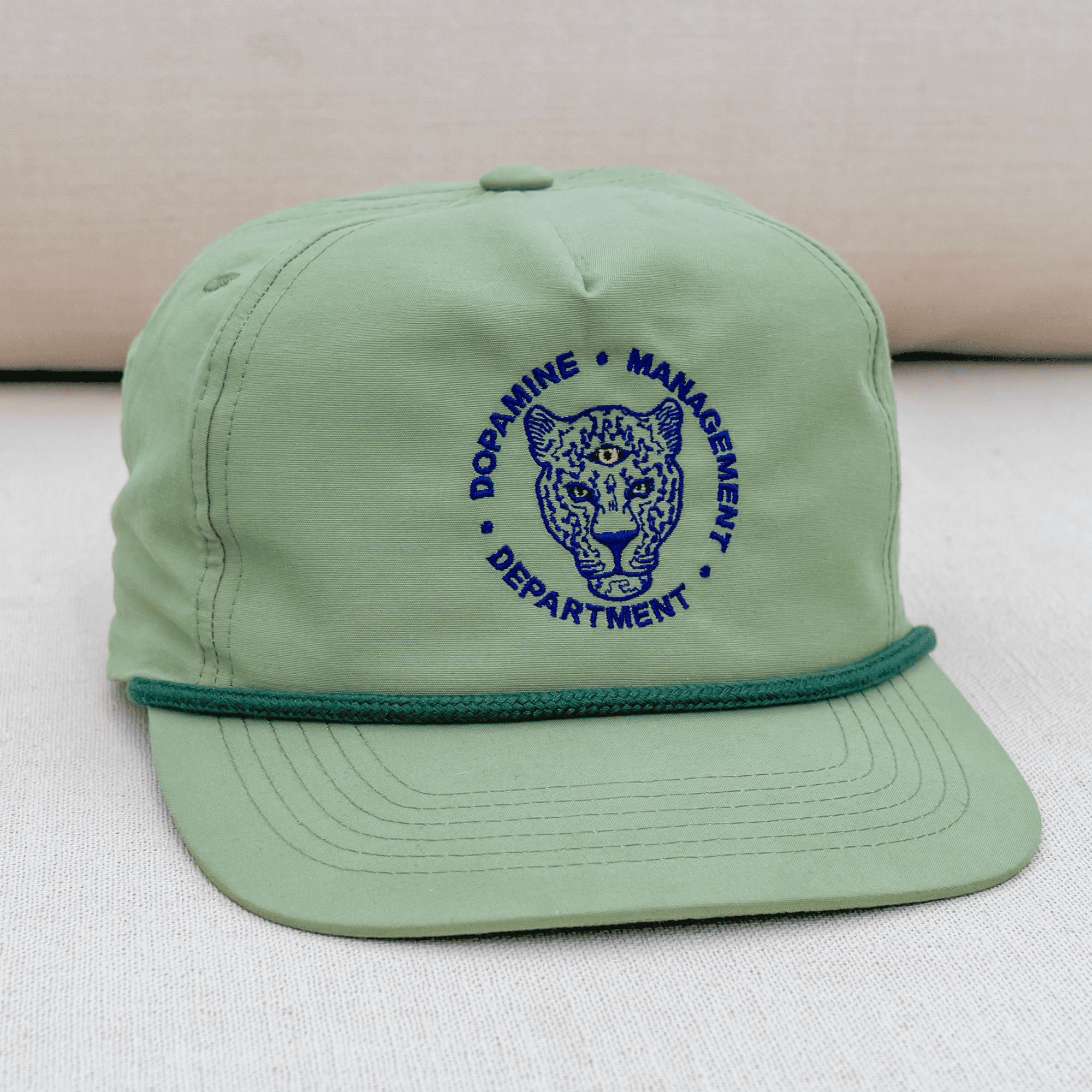 Green cap with blue embroidered design on a light background