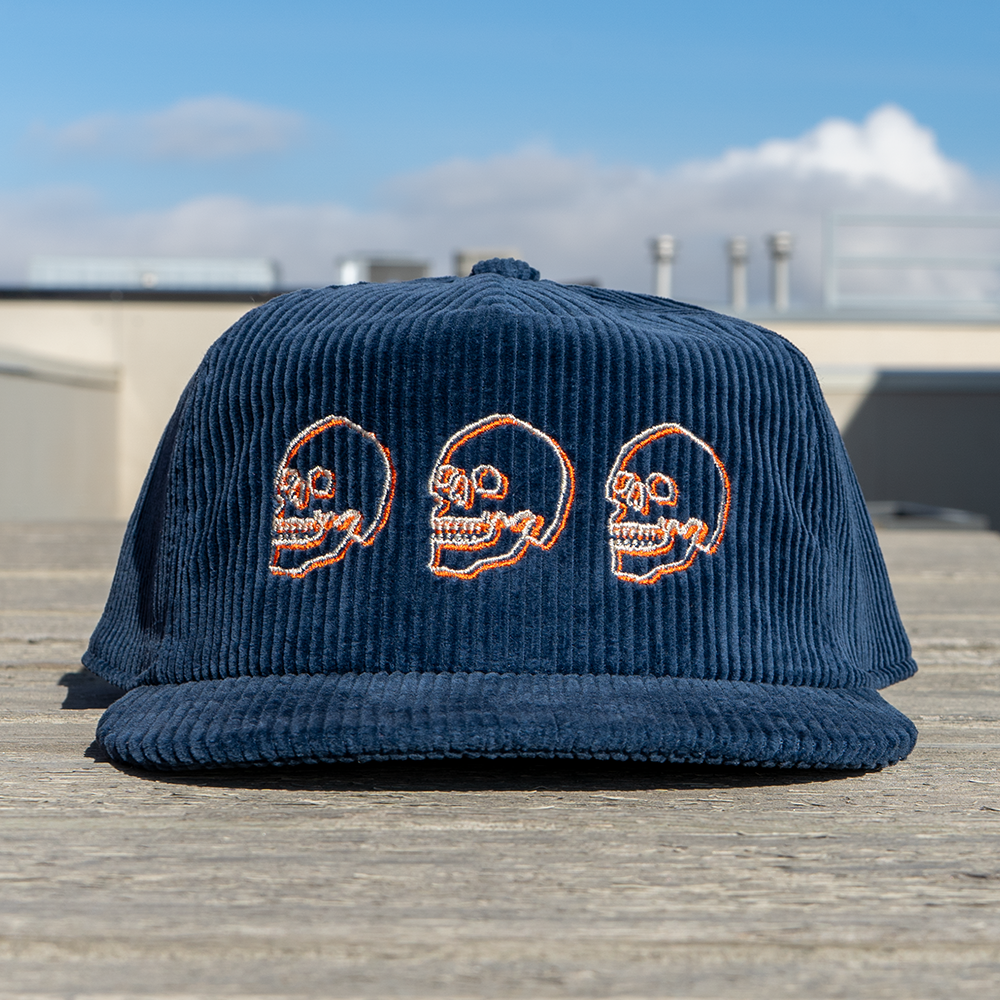 Navy blue corduroy cap with cream and orange embroidered skulls