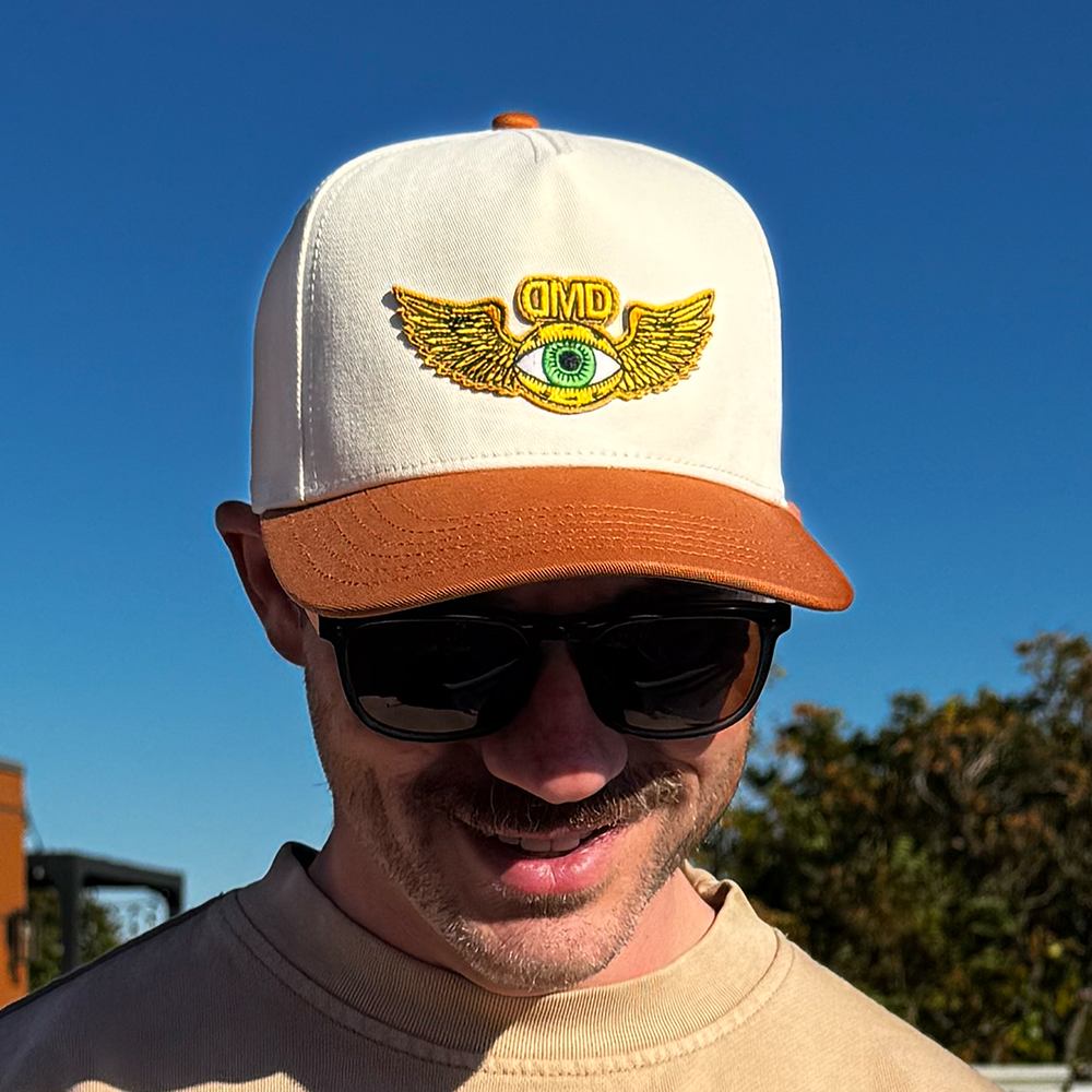 Outdoor portrait of model wearing Flying Eye Two-Toned Hat by DMD, beige and caramel snapback