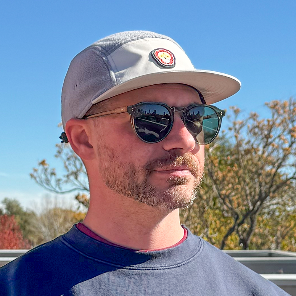 Front view of model wearing Skull Flower Fleece 5 Panel hat showing PVC skull flower patch