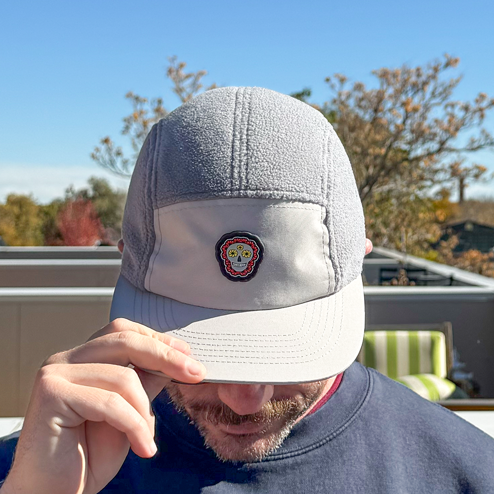 Front view of model looking down wearing Skull Flower Fleece 5 Panel hat showing PVC skull flower patch