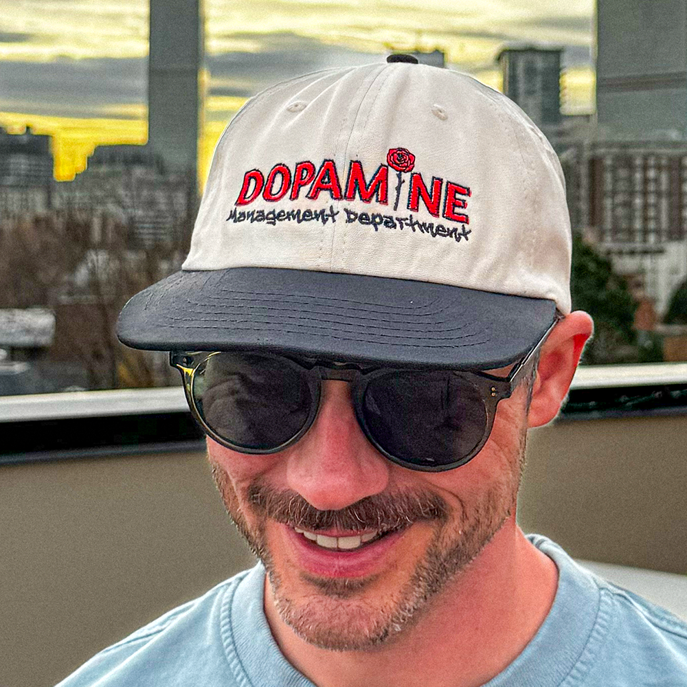 Side-angle lifestyle shot of the Rose Logo Hat worn with sunglasses.