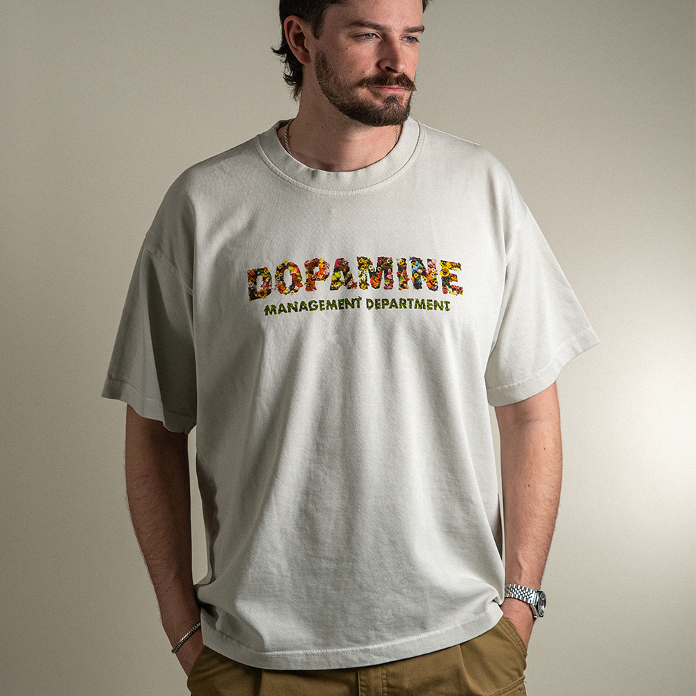 Model wearing Wallflower tee with Dopamine Management Department floral design on heavyweight cotton tee in light grey. 