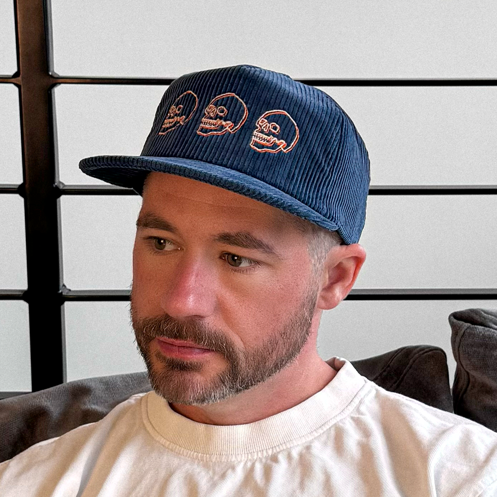 Man wearing a blue cotton corduroy cap with skull designs 