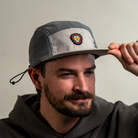 Front angled view of model wearing Skull Flower Fleece 5 Panel hat showing PVC skull flower patch