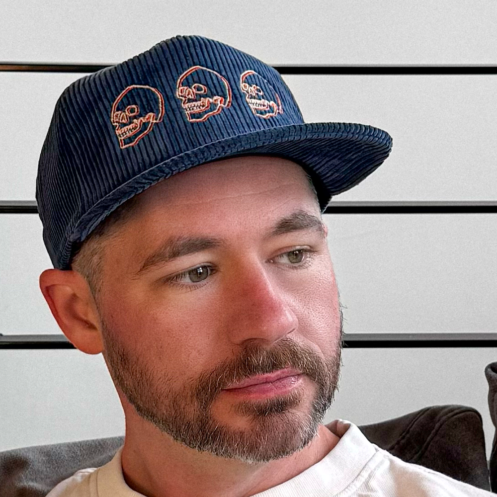 Man wearing a navy blue cotton corduroy cap with skull design embroidery 