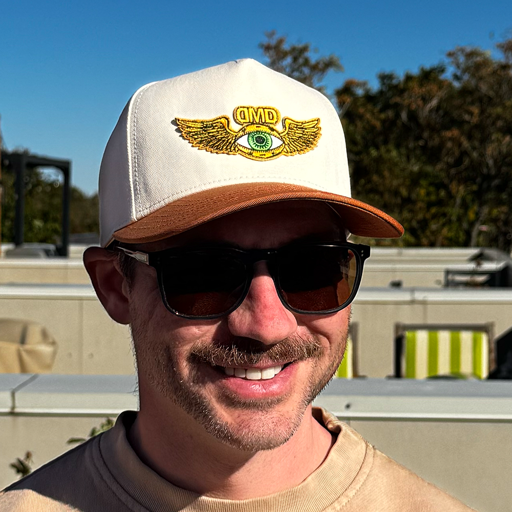 Model wearing the Flying Eye Two-Toned Hat by Dopamine Management Department with beige crown and caramel bill