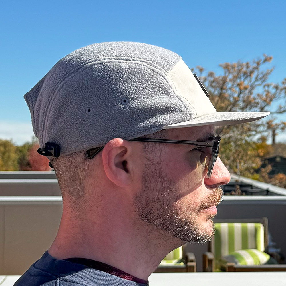 Profile view of model wearing Skull Flower Fleece 5 Panel hat in natural outdoor light