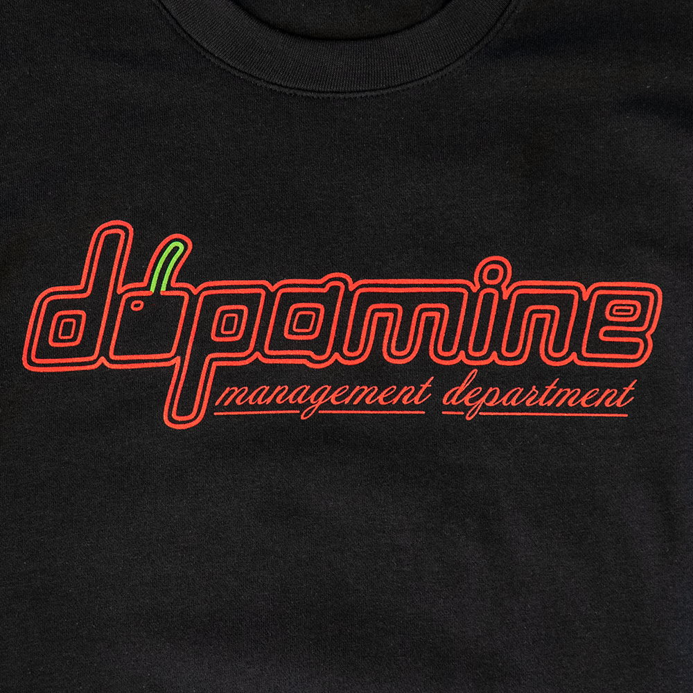 Close-up of cherry dopamine logo on women’s black fleece crewneck