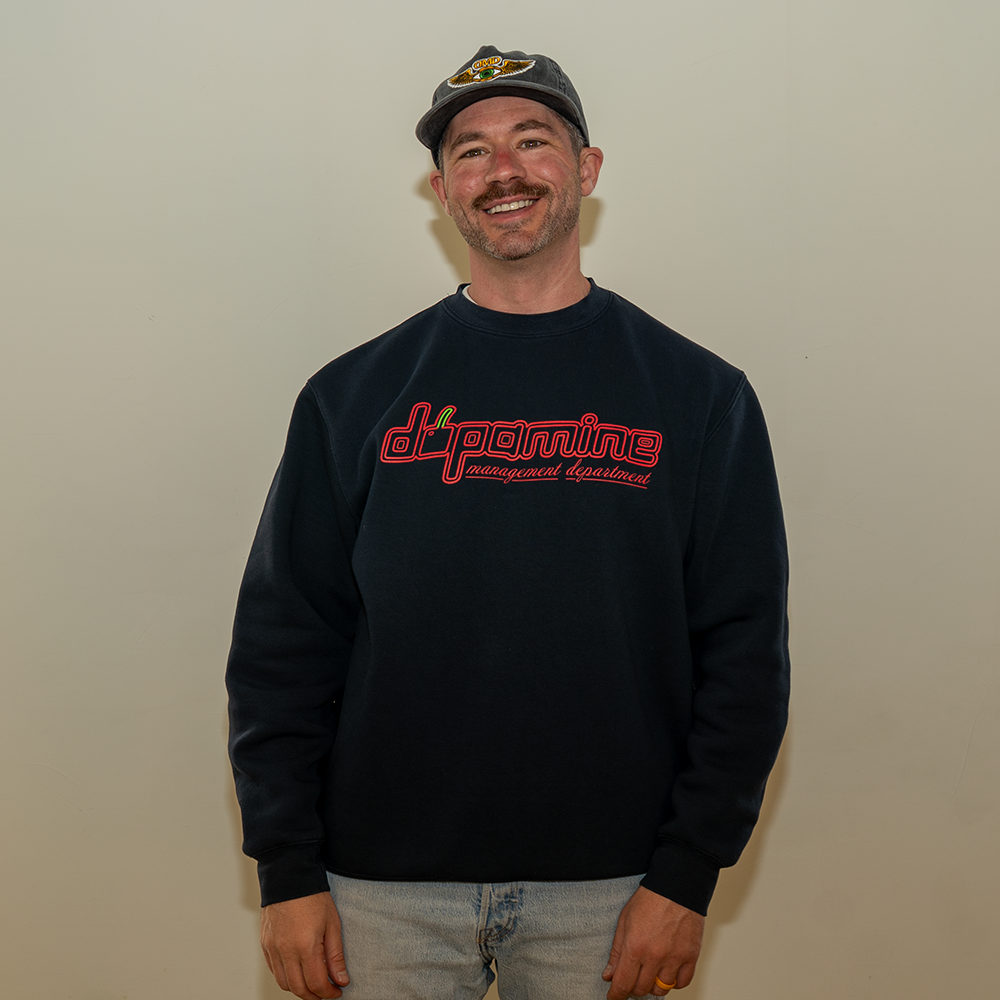 Smiling model in Dopamine Management Department cherry logo sweatshirt