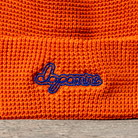 Close-up of an orange knitted fabric with 'Dopamine' embroidered in blue