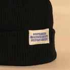 Black low profile recycled knit beanie with Dopamine Management Department label close-up