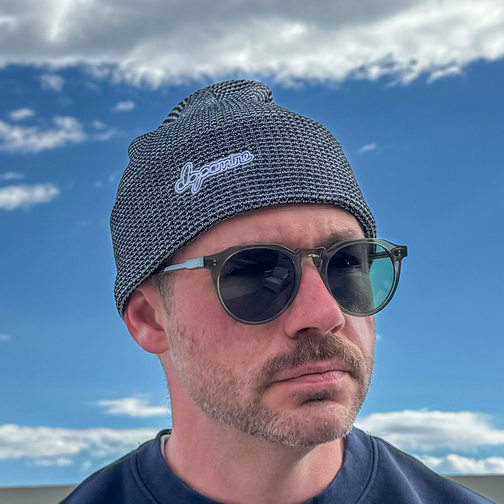 Model wearing grey & black Script Beanie against blue sky