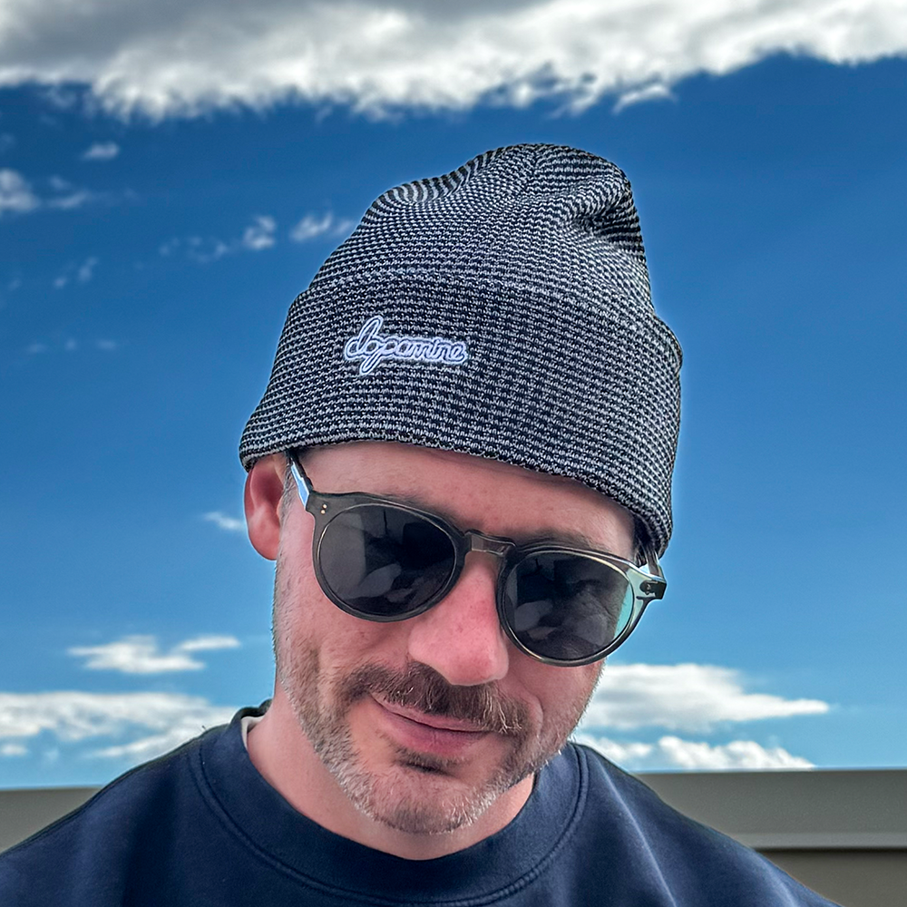 Model wearing grey & black Script Beanie against blue sky
