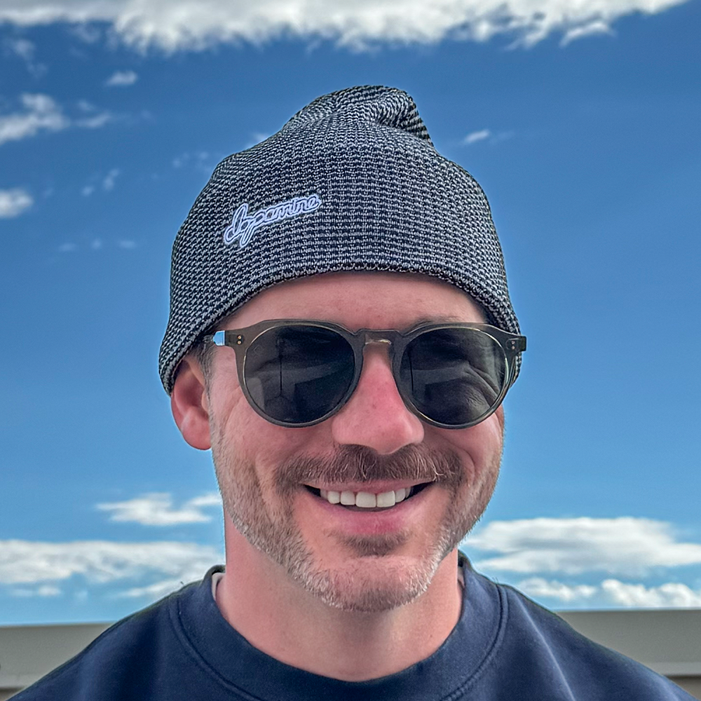 Model wearing grey & black Script Beanie against blue sky