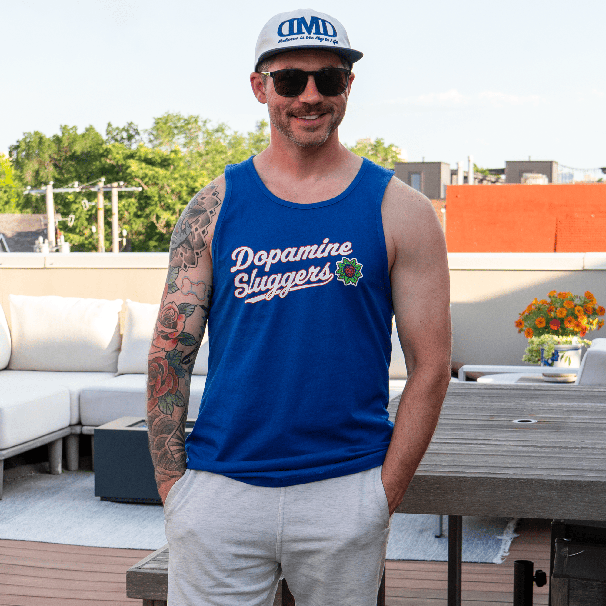 Man wearing Dopamine Sluggers tank top on rooftop in summer setting