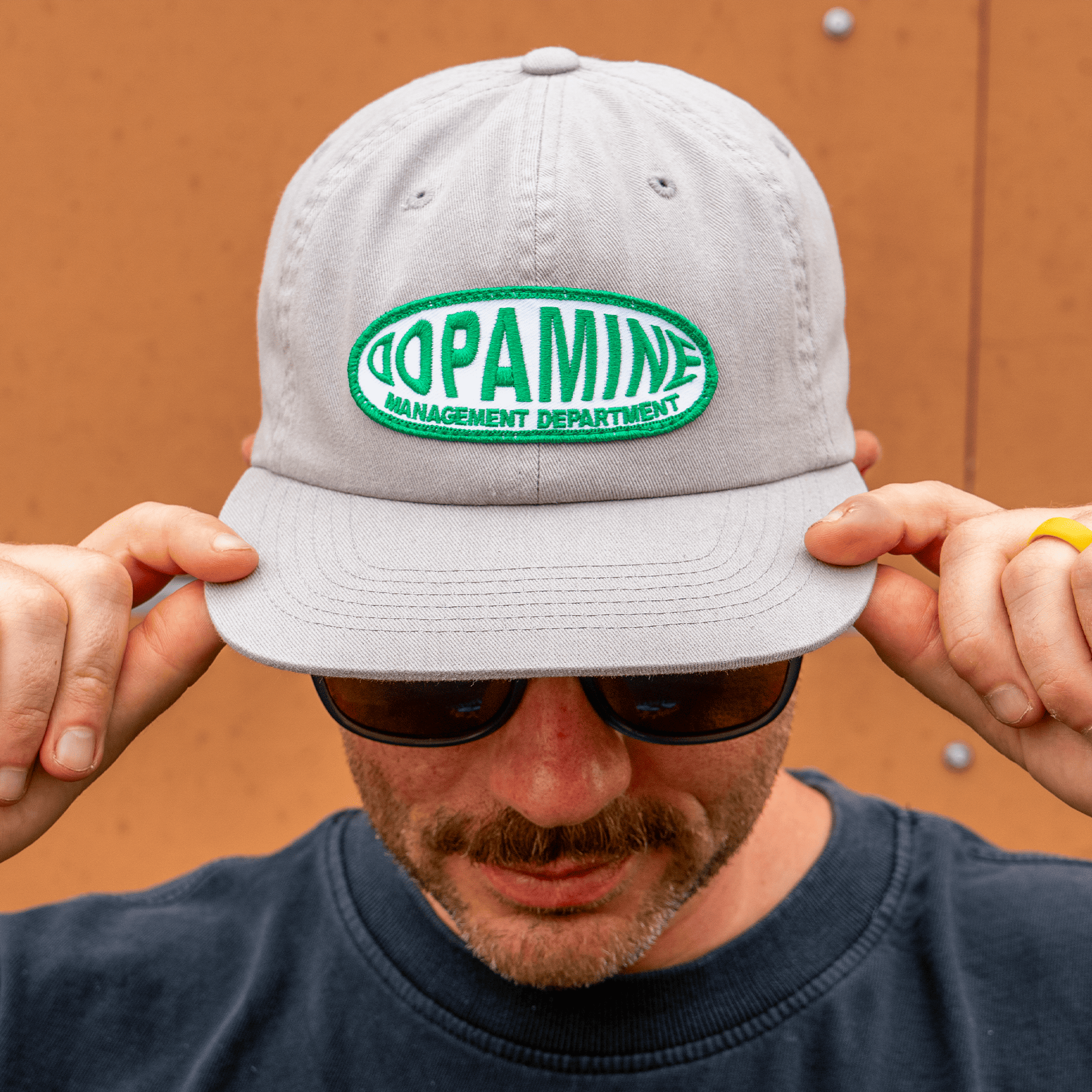 Person wearing a gray cap with 'Dopamine Management Department' logo.