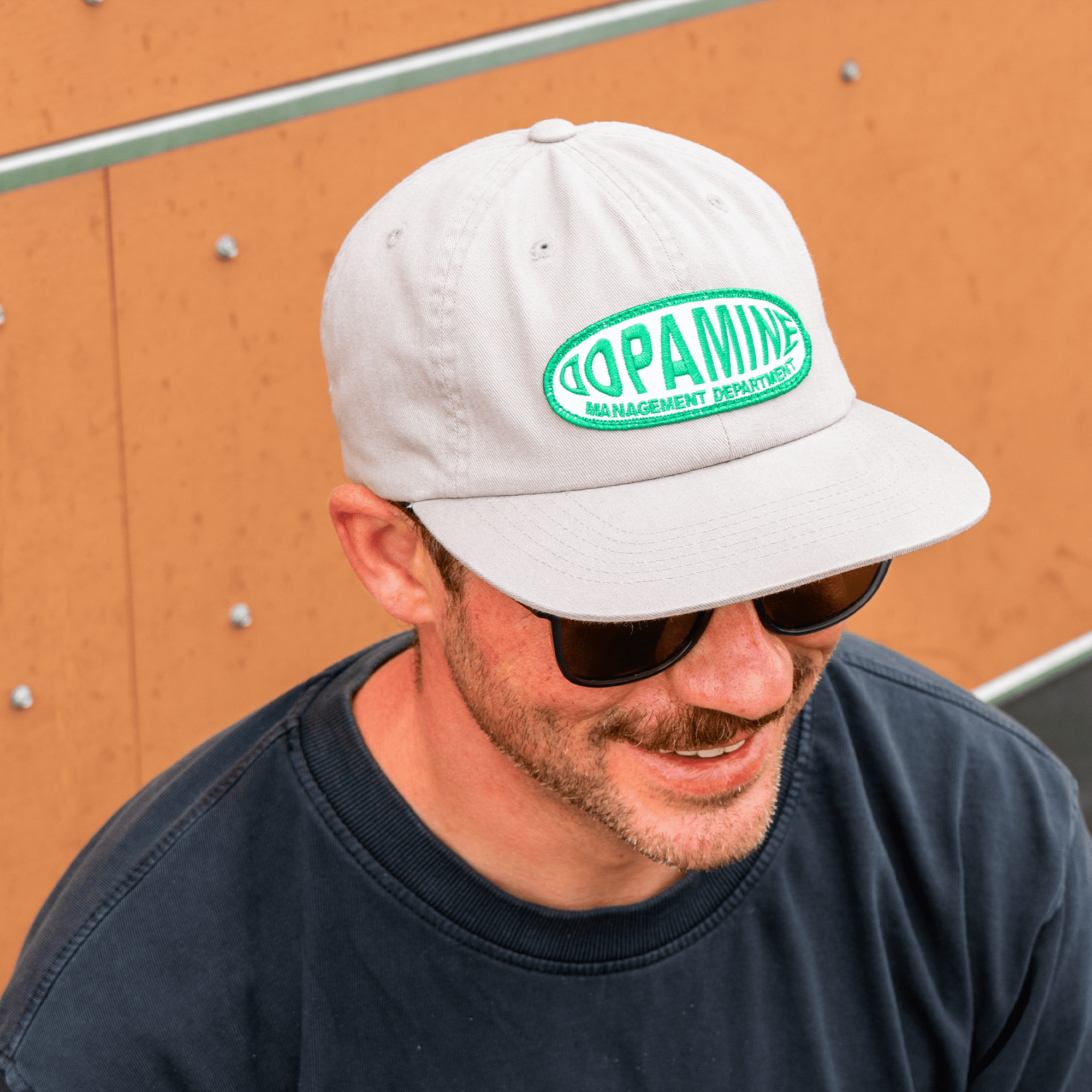 Man wearing DMD warp patch hat and sunglasses, against a wooden background